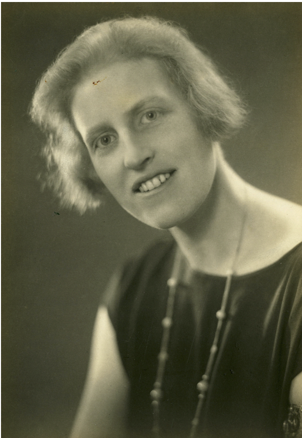 A photo of Winifred Holtby. She is wearing a black sleeveless dress and a long necklace with large beads.